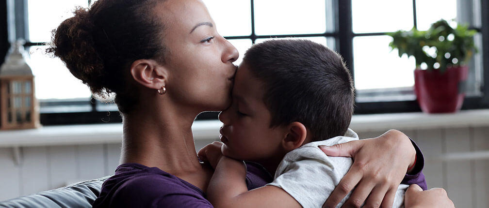 parenting Women kissing son on forehead